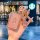 A hand holds a pink, diamond-encrusted aito huawei nfc card key cover with a teddy bear charm and keyring, set against a blur...