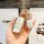 A hand holds a stylish white and gold land rover evoque key cover, featuring a decorative charm and a leather tag with ask en...