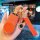 A hand holds an orange ora good cat key cover with a gold-accented design, featuring a decorative charm and free engraving op...