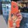 A hand holds a vibrant orange bmw leather key fob case, featuring a decorative butterfly charm and free engraving, designed f...