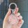 A hand holds a nio u2 key cover for nio u-ii & x, featuring a sleek silver ring with embedded crystals and a pink textured ce...