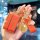 A hand holds a stylish orange leather key cover for the tank 300, featuring a 2023 new logo and adorned with gold charms, inc...