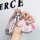 A hand holds a pink porsche key cover for panamera, cayenne & taycan, adorned with a decorative horse charm and sparkling det...
