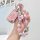 A hand holds a pink chevrolet key cover for cruze, malibu xl & trax, adorned with a decorative keychain featuring beads and c...