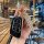 A hand holds a stylish chery qq ice cream key cover, featuring a sleek black and gold design with a decorative keychain, set ...