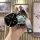 A hand holds a sleek black chery jetour dashing key cover for idm plus, featuring a cute bear charm and a stylish strap with ...