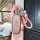A hand holds a tengshi d9/n7/n8 key cover, showcasing its sleek, metallic design with a pink textured finish and a braided pi...