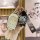 A hand holds a sleek, white key cover for the 2024 jetour x70 plus, featuring a cartoon bear charm and a stylish strap with f...