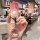 A hand holds a sleek, gradient red peugeot car key cover with a decorative ring, showcasing its front view in a modern café s...