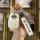 A hand holds a toyota corolla ex key cover for vios, featuring a white leather design with a cute face and the toyota logo, a...