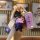 A hand holds a purple foton tuoyano key cover shell with a cute bear charm and a matching strap, set against a stylish backdr...