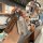 A hand holds a sleek wuling key cover with a wooden strap, showcasing its front view in a modern café setting. the metallic d...