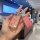 A hand holds a pink volkswagen key cover with a glittery design, featuring a decorative keychain and tag labeled karaoke keyc...