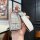 A hand holds a sleek, silver key cover for the buick enclave plus 2025, featuring a glittery finish and a white leather keych...