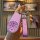A hand holds a pink nio es6 key cover featuring a cartoon design with four icons, a quilted leather strap, and a decorative k...