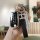 A hand holds a sleek black dongfeng fengguang 580 key cover with a leather strap and a decorative h charm, set against a mode...