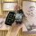 A hand holds a vinfast v3/v5/v7/v8 key cover with a sleek black design, accompanied by a cute bear-shaped keychain and a patt...