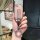 A hand holds a wuling hongguang mini ev key cover with a pastel pink, textured design and a silver keychain, styled like a re...
