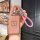 A hand holds a stylish zeekr card key cover with a pink textured design and zeekr logo, featuring a braided pink strap and a ...