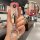 Hand holding a sleek, gradient pink chevrolet cruze key cover with a decorative cat-ear keychain, shown in front view.