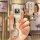 A hand holds a sleek, cream-colored peugeot key cover with a metallic lion emblem and a clear key ring, showcasing the front ...