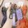 A hand holds a volkswagen passat 2022 key fob encased in a purple protective cover, featuring a matching leather strap with t...