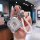 A hand holds a sleek, silver baojun kiwi ev key cover with a braided white strap and a decorative skull charm, showcasing its...