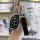 A hand holds a sleek hyundai 4-button key cover with silver trim, featuring a black leather strap and a personalized keychain...