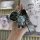 A hand holds a toyota fj cruiser prado 3-button key cover, featuring a stylish gray bear charm with blue x eyes and a matchin...