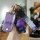 A hand holds a purple leather key cover with a sleek design, accompanied by a glittery bear charm and a stylish wrist strap f...