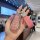A hand holds a stylish pink key cover for geely emgrand, starry, boyue & binrui, featuring a glittery design and a matching l...