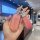 A hand holds a stylish huawei aito m7 key cover, featuring a glittery pink leather design with a decorative bow and clear but...