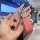 A hand holds a pink mercedes-benz e300l key cover with a glittery finish, featuring a silver emblem and a matching keychain w...