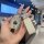 A hand holds a mercedes-benz e300l key cover with a sparkling design and a matching leather tag, set against a modern, well-l...