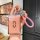A hand holds a stylish aito m7/m9 key cover with a pink textured design and metallic logo, featuring a braided pink strap and...