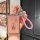 A hand holds a pink hongqi hs7 hs5 key cover with a glittery finish, featuring chinese characters and a bottle design, attach...