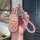 A hand holds a pink jeep key cover for compass, cherokee, renegade, and grand cherokee, featuring a braided pink strap and a ...