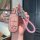 A hand holds a pink jeep key cover for compass, cherokee & grand cherokee, featuring a glittery texture and a matching braide...