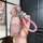 A hand holds a stylish zerorun c11 key cover for 2024 models, featuring a pink glitter design and a braided pink strap.