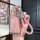 A hand holds a pink lexus key cover with a glittery finish, featuring a silver outline and a braided pink strap with a decora...