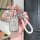 A hand holds a chevrolet cruze key cover with a sleek, textured design, accompanied by a white braided rope and a decorative ...