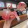 A hand holds a red volvo key cover with a gradient design, featuring a cute bear charm and a wrist strap, displayed in a café...
