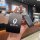 A hand holds a sleek black ora iq nfc key cover, featuring the brand logo and a decorative charm, designed for 2018–2024 elec...