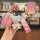 A hand holds a pink cadillac key cover with a gradient design, featuring a cute bear charm and a wrist strap, shown from the ...