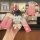 A hand holds a pink toyota key cover with a gradient design, featuring a cute bear charm and a front view inset showcasing it...