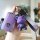A hand holds a purple mazda 3 key cover with a sleek design, accompanied by a charming bear-shaped keychain and a stylish str...