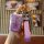 A hand holds a stylish purple key cover for the landwind x7, featuring a quilted strap and a decorative keychain with a numbe...