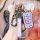 A hand holds a purple mg gs gt key cover (2015–2019 model) with a sleek remote protector, leather strap, and carabiner, showc...