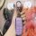 A hand holds a purple gac trumpchi gs4 key cover with a sleek leather design, featuring a silver keychain and a modern car ke...