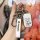 A hand holds a suzuki jimny key cover, featuring a sleek white leather design with a suzuki logo tag and a carabiner, set aga...